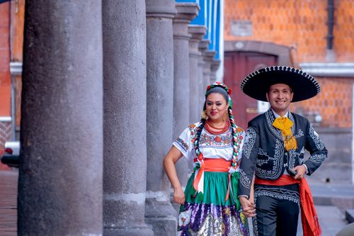 Free A couple wearing traditional Mexican costumes walking through a colonnade in Puebla, Mexico. Stock Photo