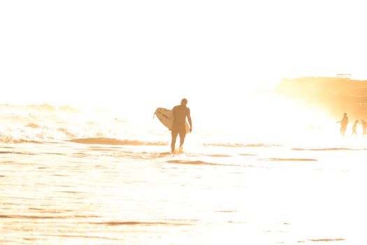 Overexposed Photo of Man Walking with a Surfboard