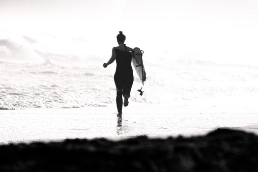 Woman Running into Sea with Surfboard