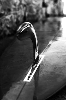 Black and white close-up of a surfboard fin, showcasing elegant design and texture.