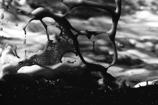 An artistic black and white close-up of sea foam splashing dynamically.
