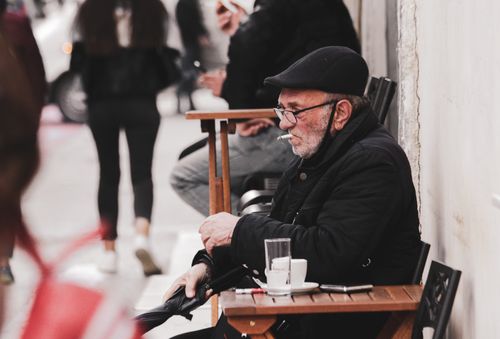 Free An elderly man in a black jacket smoking outside a cafe in Tirana, Albania. Stock Photo