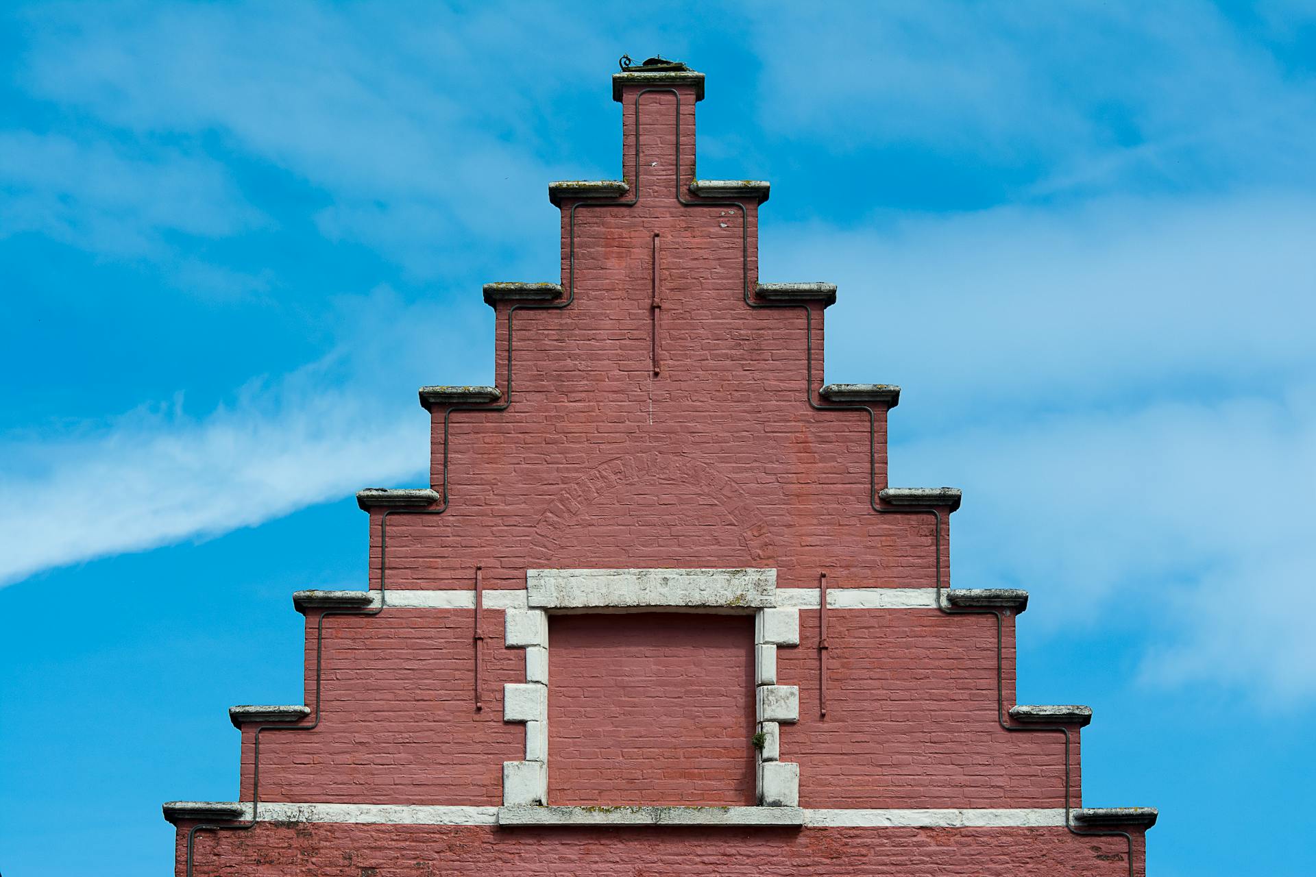 Elevated view of a gable brick building facade with sky background, showcasing traditional architectural design.