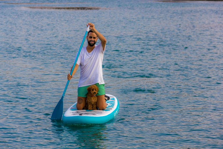 A Man Paddle Boarding With His Dog