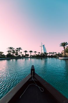 View from a boat towards the iconic Burj Al Arab in Dubai during sunset.