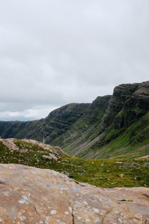 Free Breathtaking view of rugged mountains and lush grasslands beneath a cloudy sky. Stock Photo