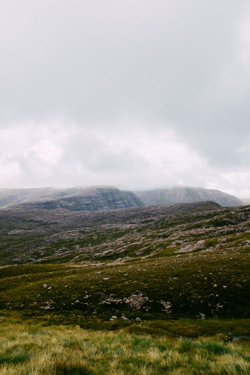 Free A peaceful mountain landscape with rolling hills and grass under an overcast sky, perfect for nature lovers. Stock Photo