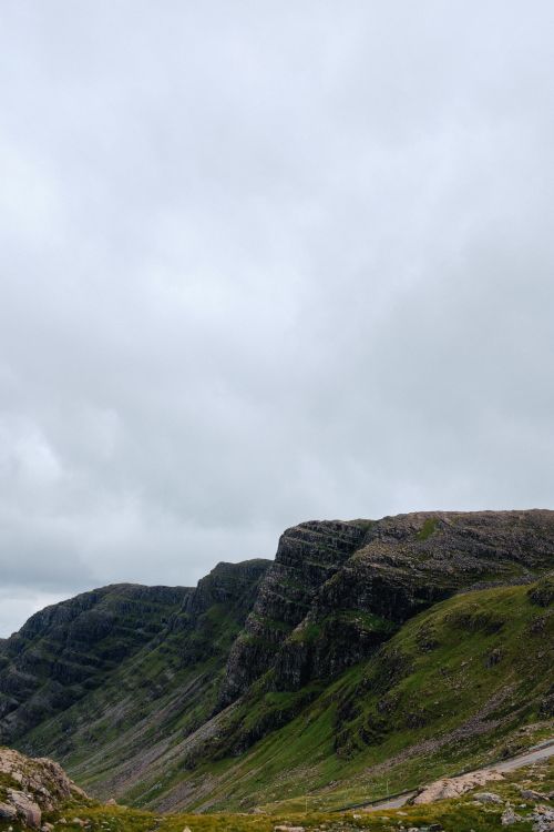 Free Dramatic mountain landscape with grassy slopes and cloudy skies, perfect for nature enthusiasts. Stock Photo