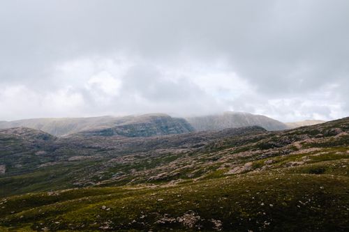 Free Expansive mountain range with lush greenery beneath a cloudy sky, perfect for nature enthusiasts. Stock Photo
