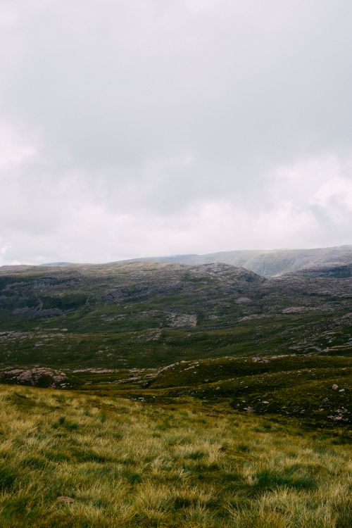 Free Peaceful mountain view with lush grasslands and cloudy sky, perfect for nature lovers. Stock Photo