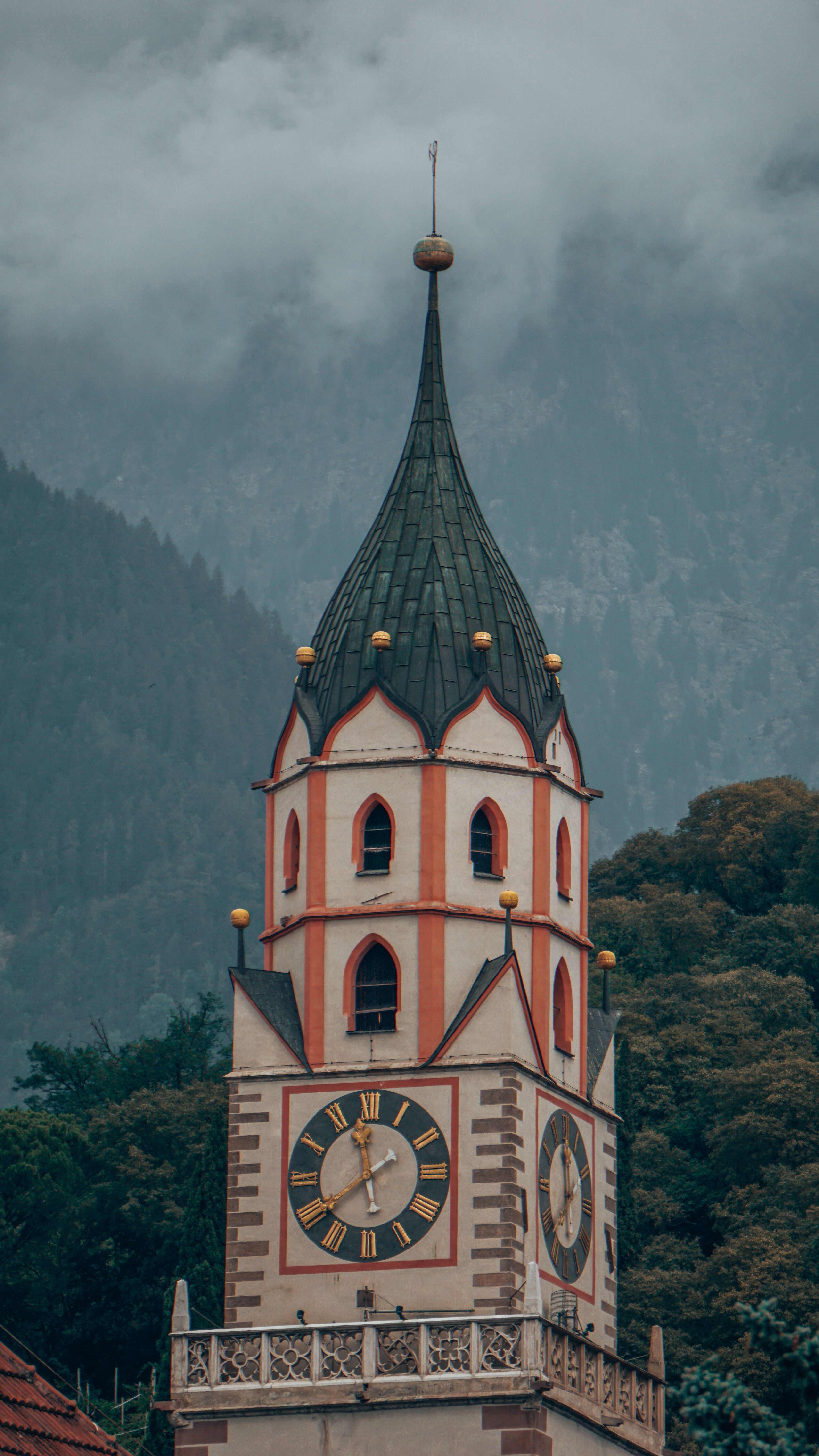 Gothic church tower amidst misty mountains in Tyrol, capturing serene alpine essence.