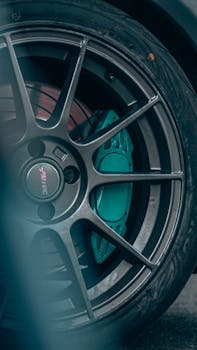 Detailed view of a car's alloy wheel and turquoise brake pads, emphasizing design and performance.