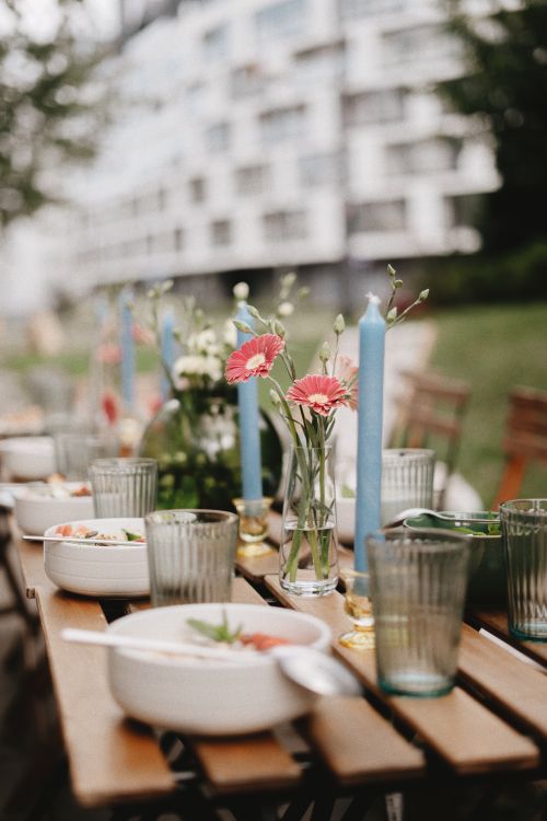 Free Elegant outdoor dining scene with floral centerpiece and candles on rustic wooden table. Stock Photo