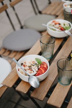 A nutritious outdoor breakfast setting with bowls of fresh fruits and oatmeal.