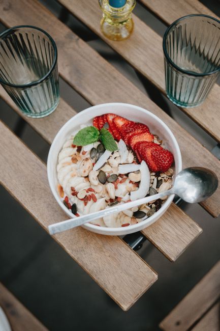 Creative close-up of a nutritious breakfast bowl with fruits, nuts, and seeds on a wooden table.