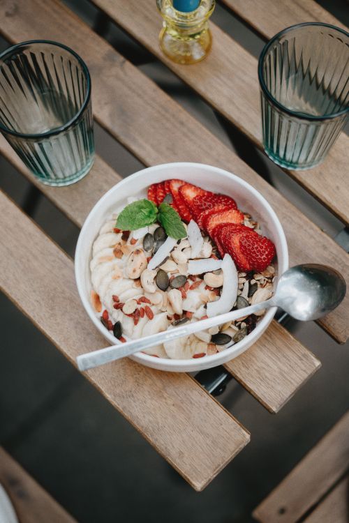 Free Creative close-up of a nutritious breakfast bowl with fruits, nuts, and seeds on a wooden table. Stock Photo