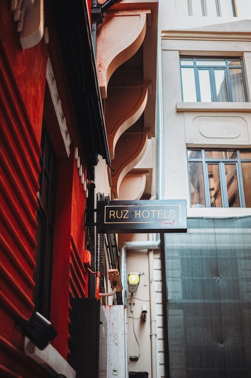 Free Vertical shot of a city alley featuring a contrasting hotel signboard between red and white buildings. Stock Photo