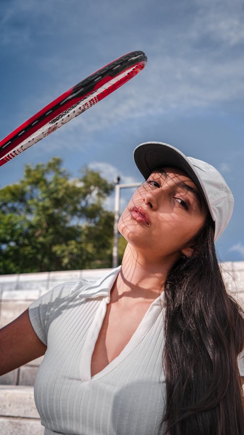 A Woman in White Shirt Holding Red and Black Tennis Racket