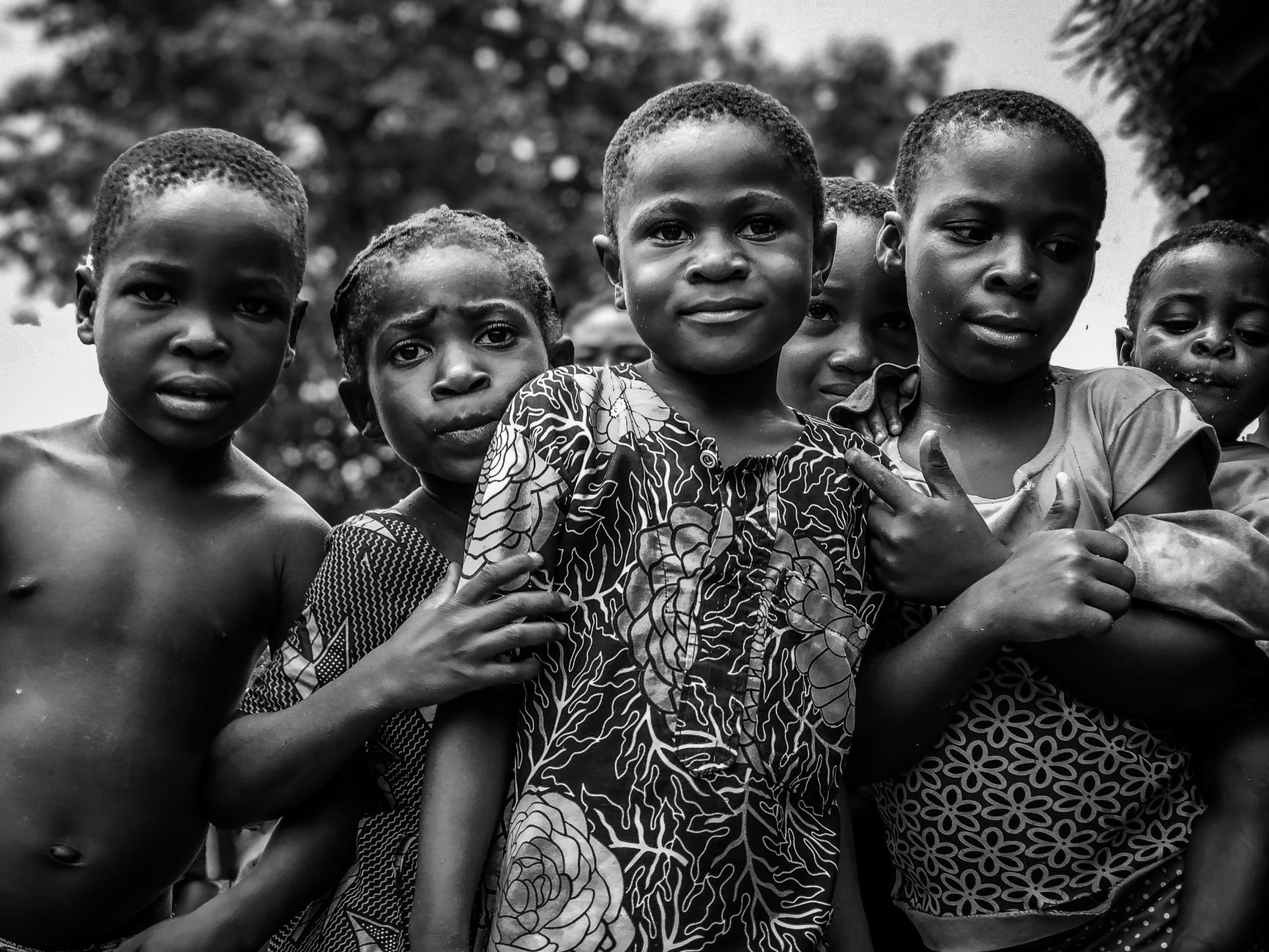 Heartwarming black and white photo of smiling African children standing together in an outdoor setting.