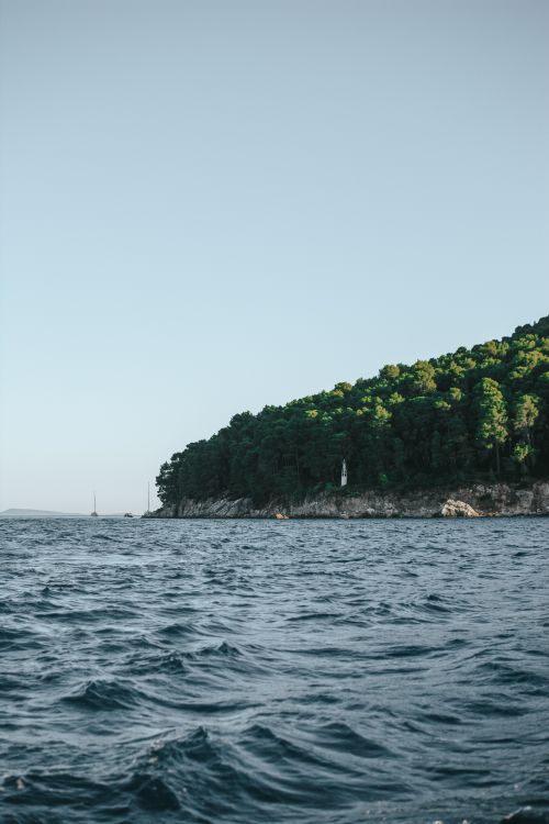 Free A serene coastal view featuring an island with lush greenery and a calm sea. Stock Photo