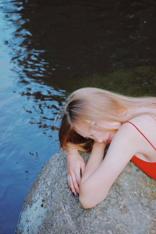 Blonde Woman Lying on a Rock by the Water 