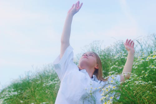 A Woman in a Flower Field Reaching for the Sky