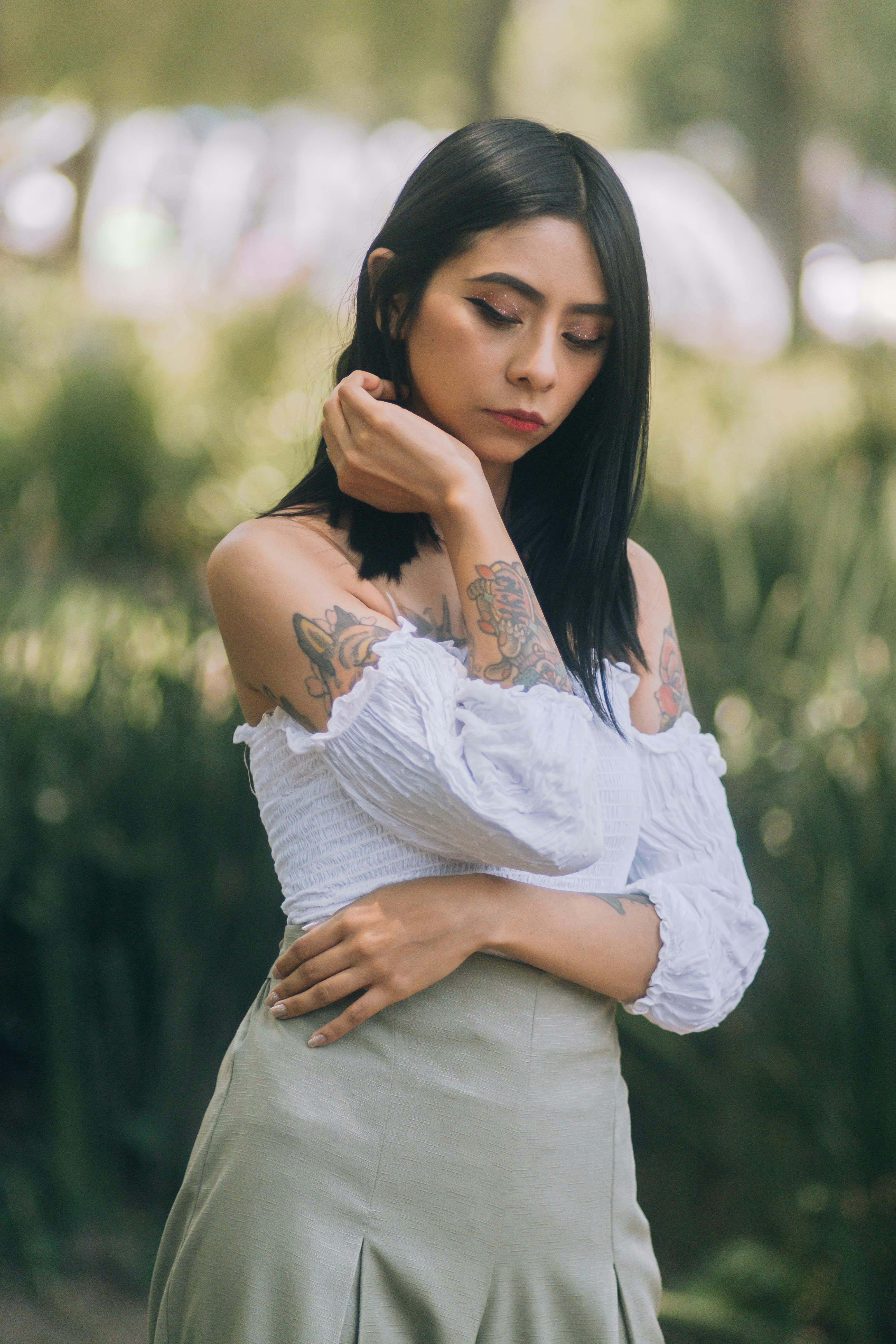 portrait of a mexican girl in a park with black hair wearing a white shirt and a green skirt with a background of green plants