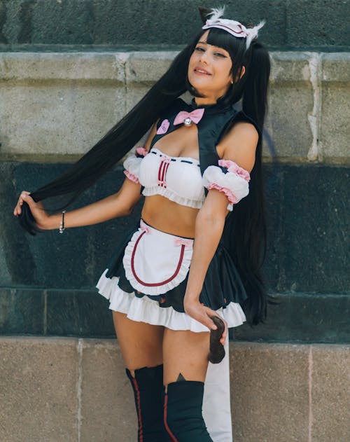 Portrait of a Mexican girl doing a maid cosplay with a brick wall in the background.