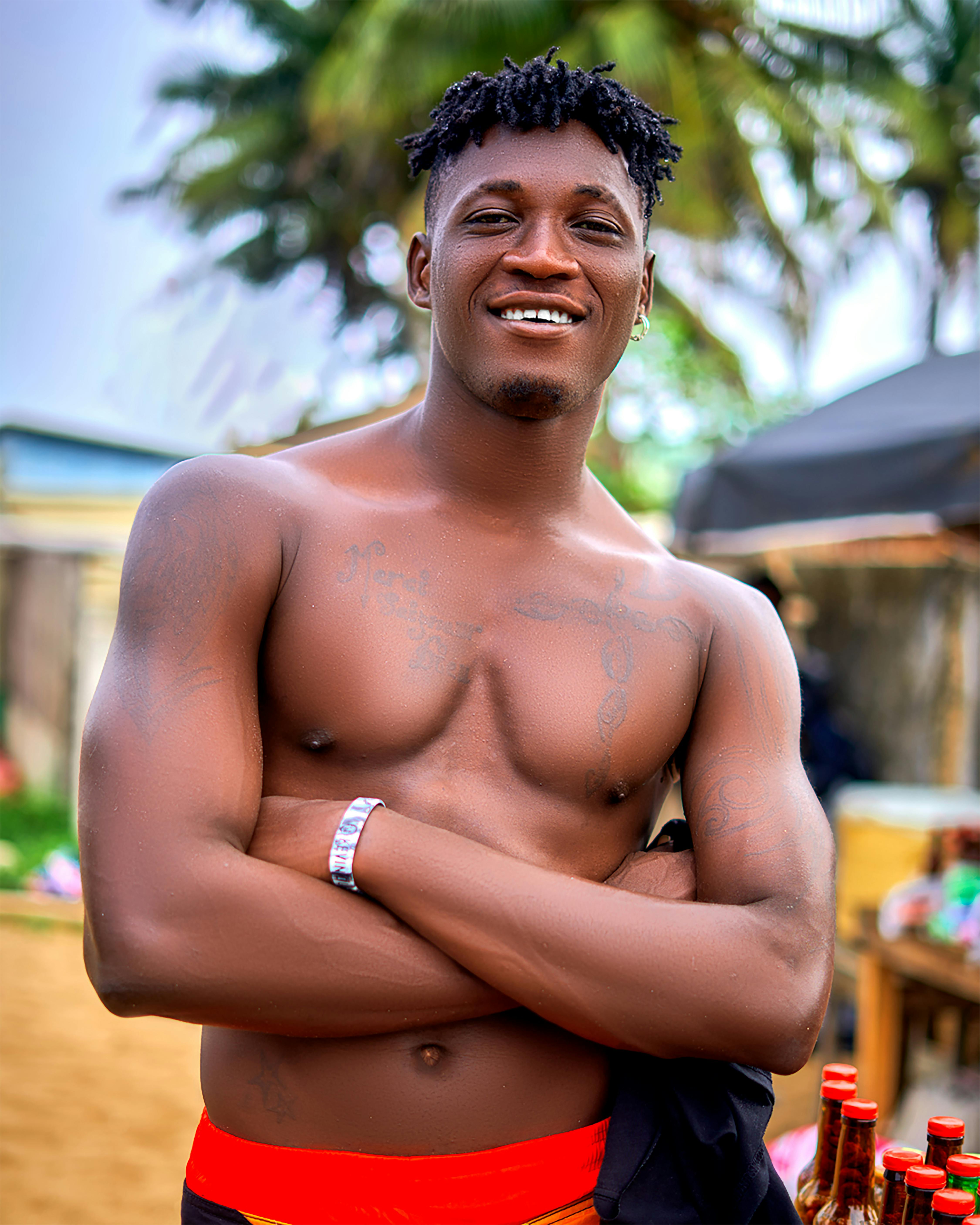 Portrait of a smiling, tattooed man with dreadlocks at a beach in Grand-Bassam, Côte d'Ivoire.
