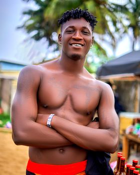 Portrait of a smiling, tattooed man with dreadlocks at a beach in Grand-Bassam, Côte d'Ivoire.