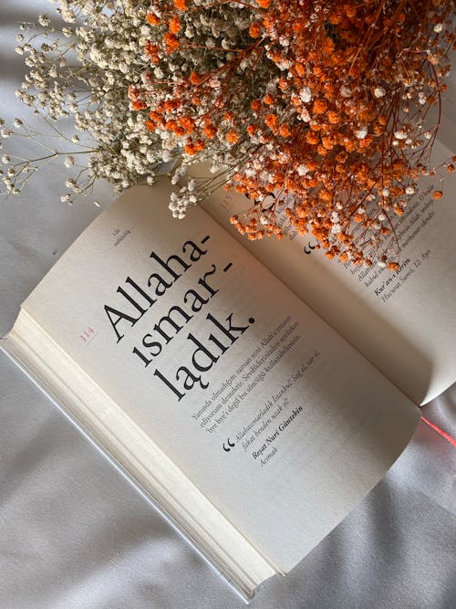 Opened Book with Bouquet of Blossom Flowers Lying on a White Tablecloth