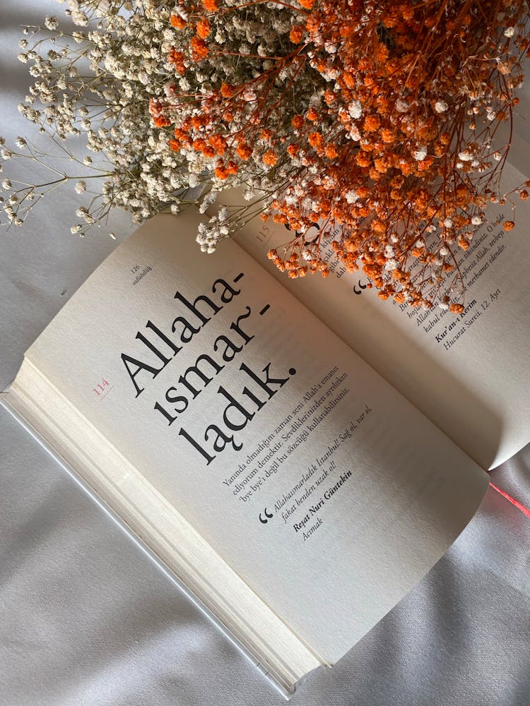 Opened Book With Bouquet Of Blossom Flowers Lying On A White Tablecloth