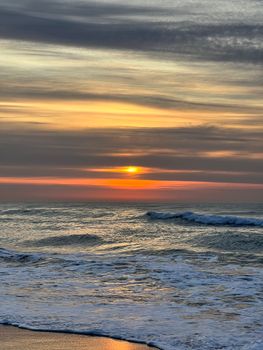 A tranquil beach sunset with stunning orange hues reflecting on the waves.