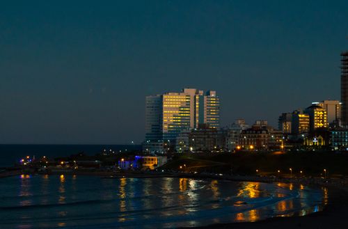 Free A vibrant skyline view of Mar del Plata, Argentina at twilight with city lights reflecting on the sea. Stock Photo