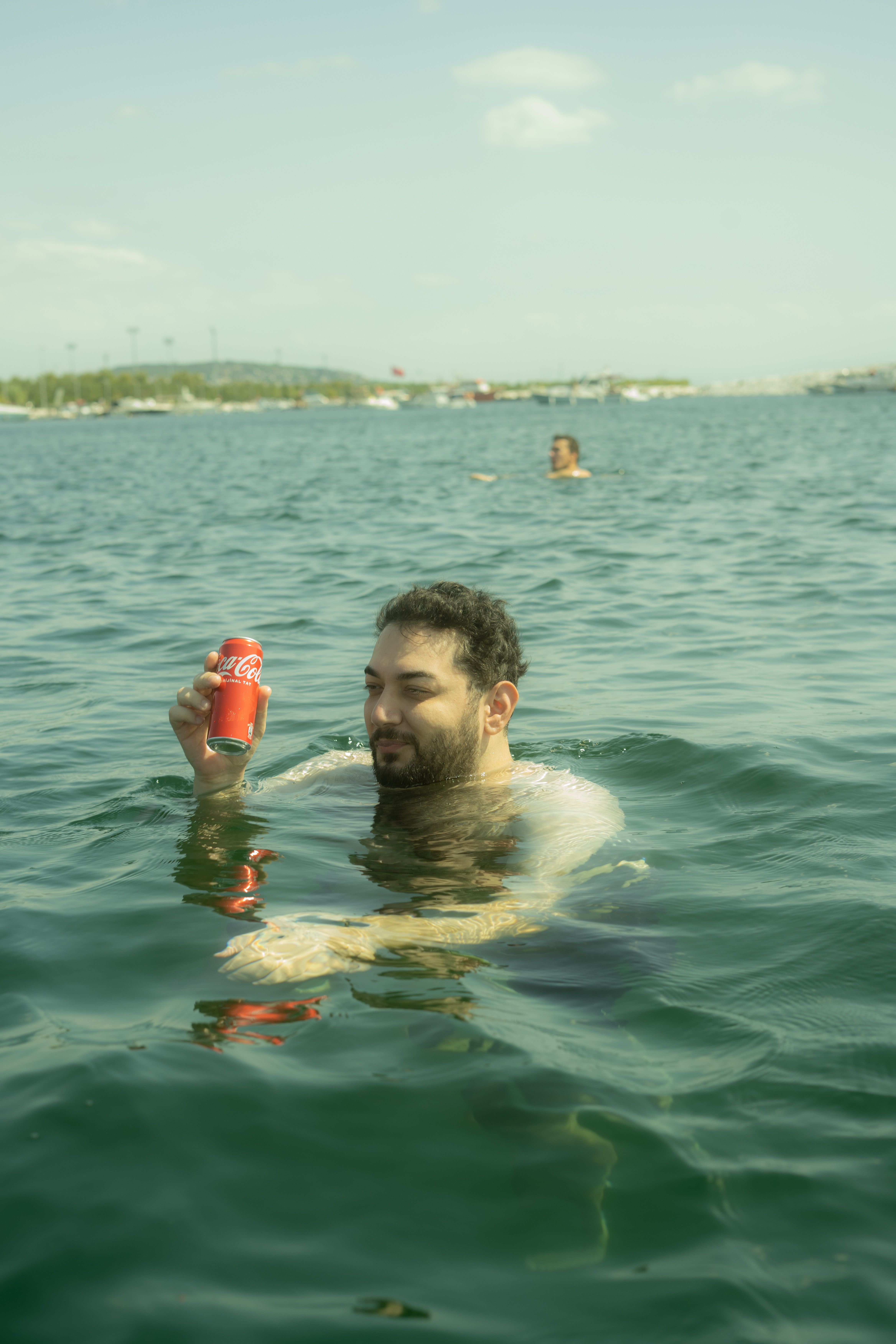 Man relaxing in the Bosphorus, İstanbul holding a Coca-Cola can, enjoying a sunny day.
