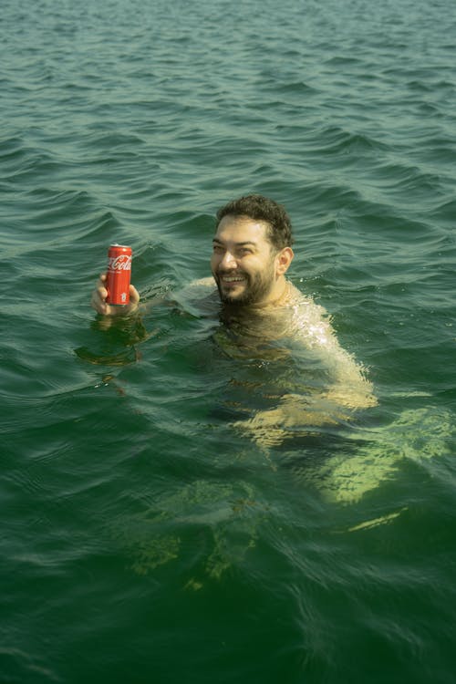 Man in the Sea Holding a Coca Cola