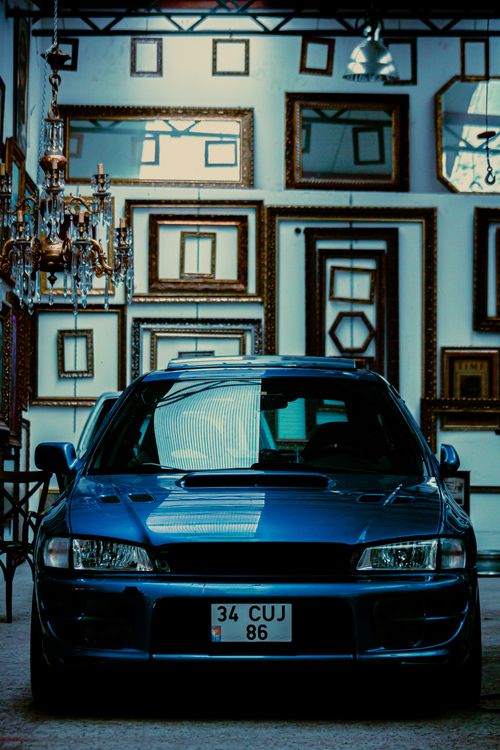 Free A vintage blue Subaru car parked inside a frame-filled gallery, showcasing unique automotive style. Stock Photo