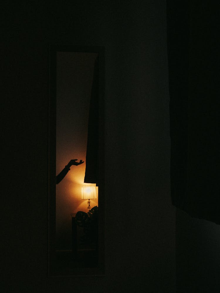 Silhouette Of Woman Hand In Dark Room With Lamp Light