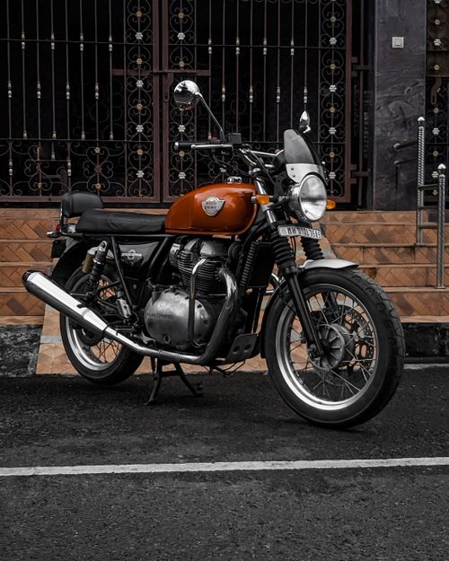 Free Vintage motorcycle with orange tank parked in front of an ornate gate in urban area. Stock Photo