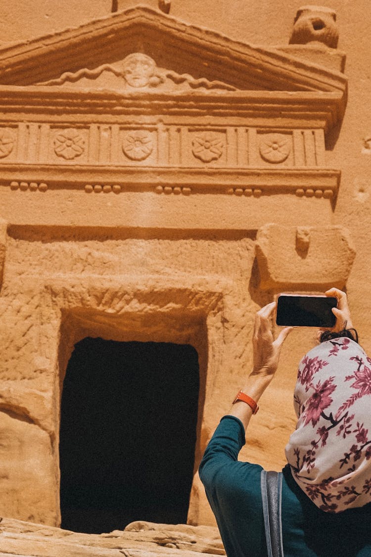 A Person Wearing Floral Headscarf Taking Photos Of An Old Ancient Structure