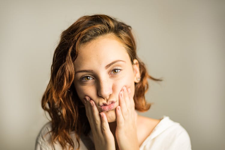 Woman Pouting While Holding Her Cheeks