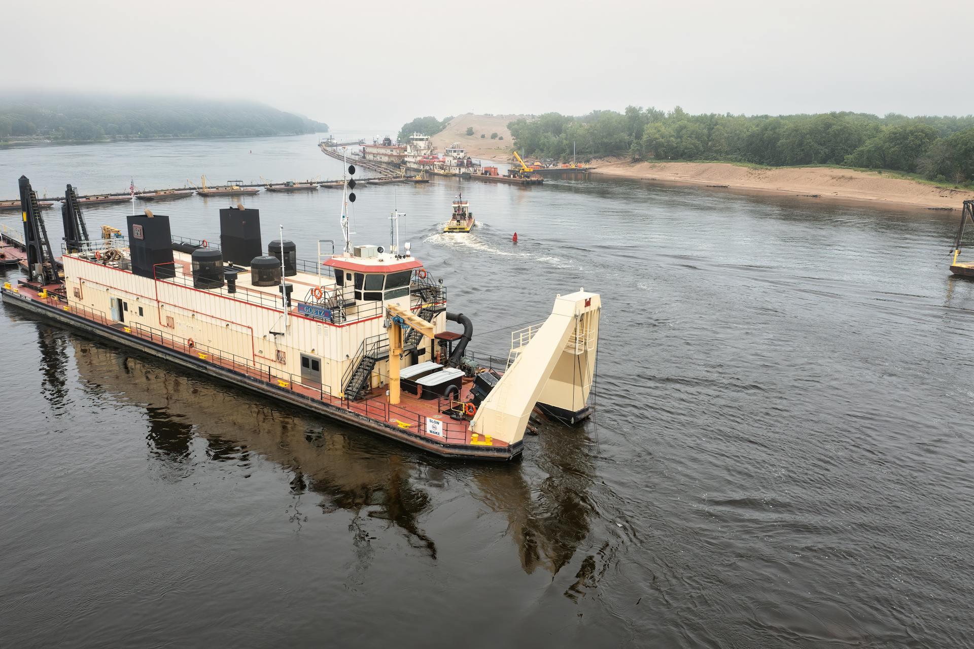 Dredging vessel navigating the Wisconsin River near Trevino, surrounded by serene water and lush greenery.