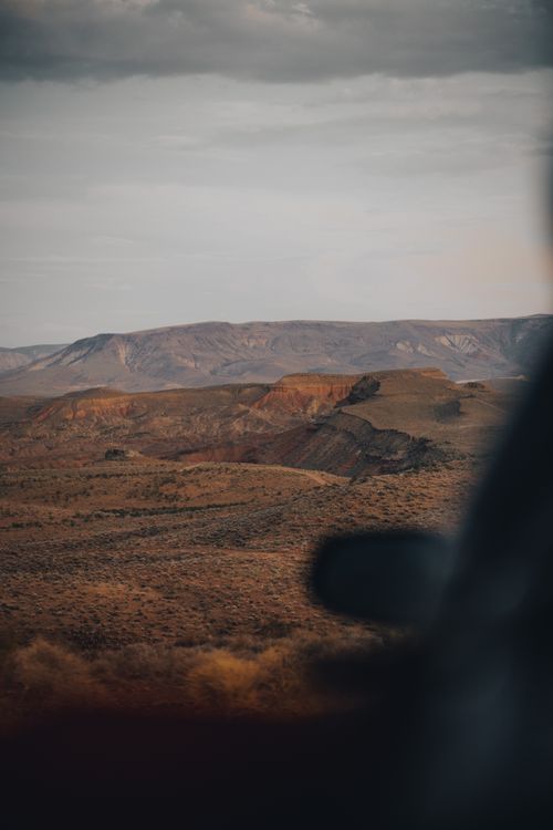 Free Explore the serene beauty of a desert landscape with sprawling hills under an overcast sky. Stock Photo