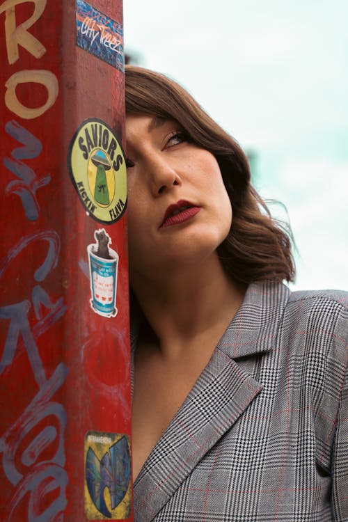 Woman in Gray Plaid Blazer Standing Near a Post