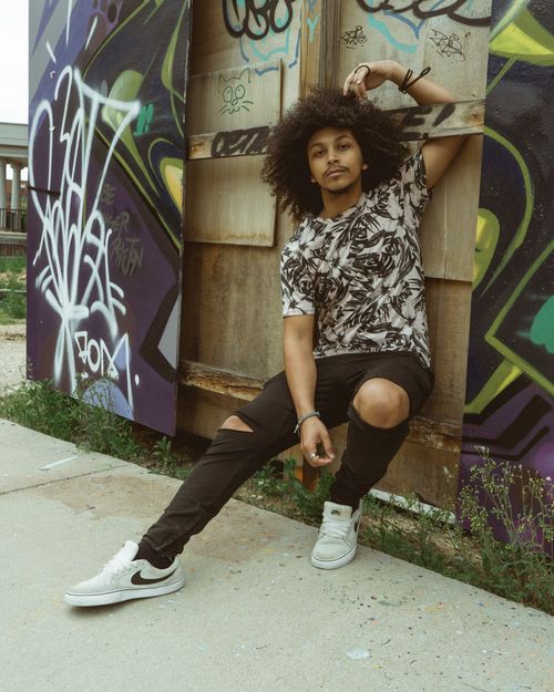 Free Trendy young man in streetwear poses against vibrant graffiti backdrop, exuding urban style. Stock Photo