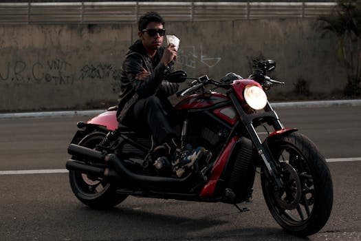 Man in black leather jacket with sunglasses sitting on motorcycle holding banknotes outdoors.