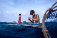 Boy Sitting on a Blue Fish Net