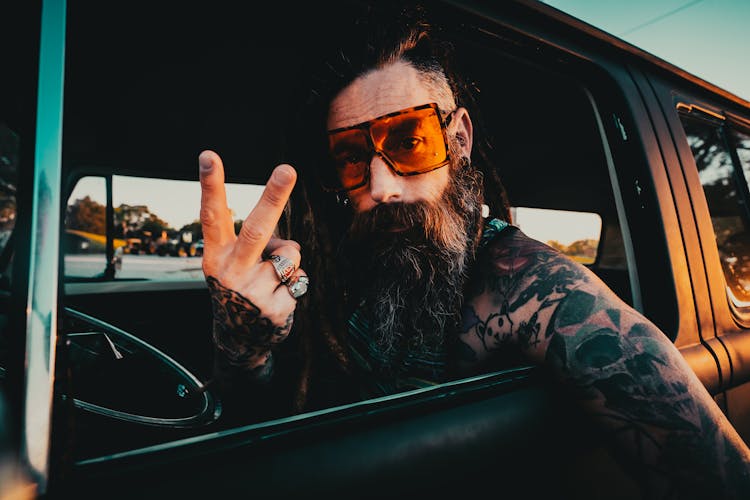 Hippie Man With Tattoos Sitting In Car