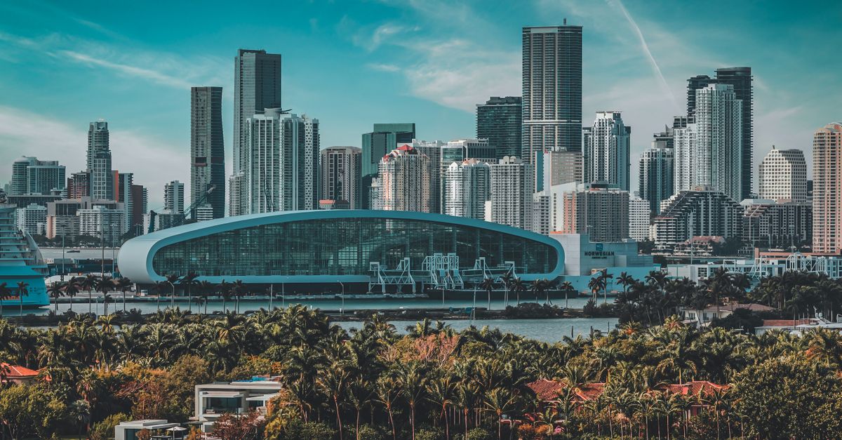 Miami downtown skyline with modern glass skyscrapers, palm trees, and waterfront on a clear sunny day