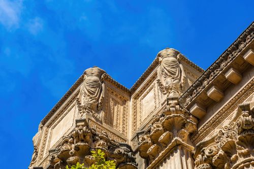 Free Low-angle view of ornate sculptures on a historic building against a blue sky. Stock Photo